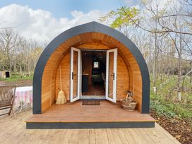 A wooden pod with open double doors on a wooden deck surrounded by trees at Hobhole in Keal Cotes near East Kirkby