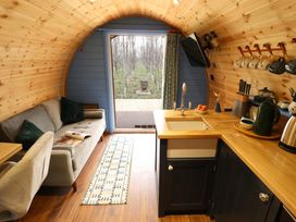A compact wooden interior with a small kitchen area and a gray sofa in a curved cabin at Hobhole in Keal Cotes near East Kirkby