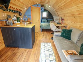 A wooden cabin interior with a kitchen island a sofa with green pillows a small dining table and a bed at Hobhole in Keal Cotes near East Kirkby