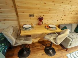 A small dining area with two chairs a wooden table set for two with plates glasses and utensils a vase with flowers and a sofa against a wooden wall at Hobhole in Keal Cotes near East Kirkby