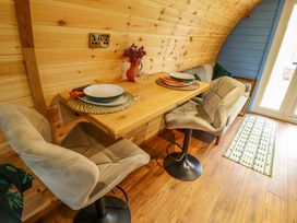 A small dining area with a wooden table set for two with chairs and a sofa in a room with wooden walls and a blue accent wall at Hobhole in Keal Cotes near East Kirkby