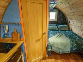 A small kitchen area with utensils and a wooden door leading to a bedroom with a bed and green bedding at Hobhole in Keal Cotes near East Kirkby