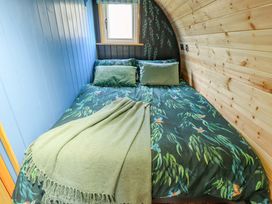 A bed with bird patterned bedding and green pillows in a room with wooden and blue paneled walls at Hobhole in Keal Cotes near East Kirkby