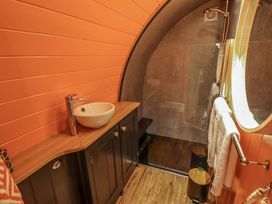 A bathroom with a round sink on a wooden countertop a glass-enclosed shower a round mirror and towels hanging on a rail at Hobhole in Keal Cotes near East Kirkby