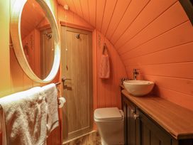 A bathroom with a wooden door a round mirror a white towel a toilet and a sink on a wooden countertop at Hobhole in Keal Cotes near East Kirkby
