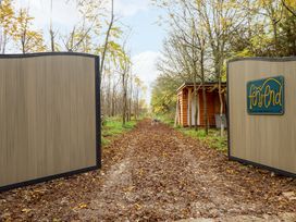 A dirt pathway covered with fallen leaves with open gates and a small wooden structure to the side with a dog standing in the distance at Hobhole in Keal Cotes near East Kirkby