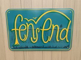 A teal sign with yellow and green lettering that reads fen ster nd mounted on a wooden wall