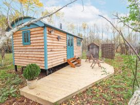 A wooden cabin with blue doors and windows on a wooden deck with chairs and a potted plant at Catchwater in Keal Cotes near East Kirkby