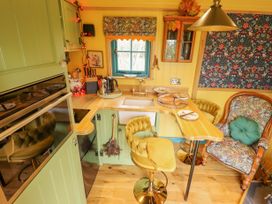 A small kitchen with green cupboards wooden countertops chairs and patterned armchair at Catchwater in Keal Cotes near East Kirkby