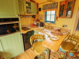 A kitchen with green cabinets yellow walls wooden countertops and two yellow bar stools at Catchwater in Keal Cotes near East Kirkby