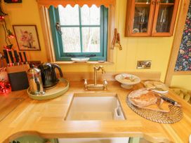 A kitchen sink with a brass faucet on a wooden countertop with a loaf of bread and a knife beside it and a kettle and coffee pot on a tray near a window at Catchwater in Keal Cotes near East Kirkby