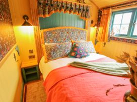 A bedroom with a double bed with floral headboard and pillows yellow walls and window curtains at Catchwater in Keal Cotes near East Kirkby