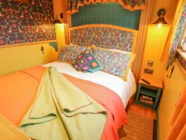 A bedroom with a bed covered with blankets and pillows next to a bedside table with books and a remote at Catchwater in Keal Cotes near East Kirkby