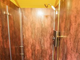 A shower area with a gold showerhead and brown textured walls at Catchwater in Keal Cotes near East Kirkby