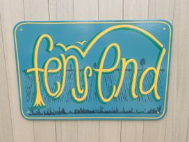A blue sign with yellow and green decorative text reading fen end mounted on a light-colored wooden wall