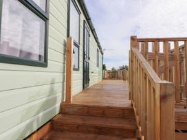 Wooden deck with stairs and railing outside a pale green building with windows and door at Ashcroft in Warton Lancashire