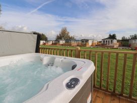 A bubbling outdoor hot tub on a wooden deck overlooking a grassy area and several mobile homes at Ashcroft in Warton Lancashire