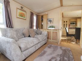 A living room with a grey sofa and cushions a rug on the floor cabinets and a view into a dining area at Ashcroft in Warton Lancashire