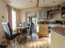 A kitchen with wooden cabinets and a round dining table with three chairs at Ashcroft in Warton Lancashire
