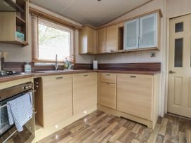 A kitchen with wooden cabinets a window with blinds and a stainless steel oven at Ashcroft in Warton Lancashire
