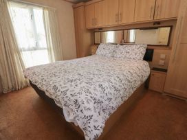 A bedroom with a bed with patterned bedding and built in wooden cabinets at Ashcroft in Warton Lancashire