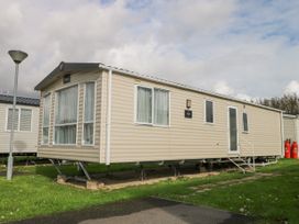 A beige mobile home on blocks with steps and windows on grass at 610 Caravan in Bognor Regis