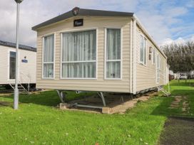 A beige caravan with large windows and curtains on a grassy plot at 610 Caravan in Bognor Regis