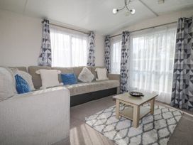 A living room with a sofa and cushions a wooden coffee table and curtains at 610 Caravan in Bognor Regis