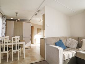 A dining area with a table and four chairs next to a beige couch with cushions in a compact living space at 610 Caravan in Bognor Regis