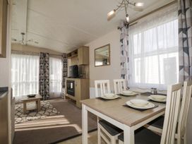 A dining area with a set table next to a living room with a coffee table tv and fireplace at 610 Caravan in Bognor Regis