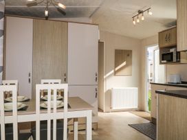 A dining area with a table set for four and a kitchen with cupboards a microwave and a toaster at 610 Caravan in Bognor Regis