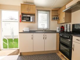 A kitchen with white cabinets a microwave a toaster kettle coffee machine and an oven at 610 Caravan in Bognor Regis