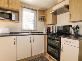 A kitchen with cabinets a microwave toaster kettle coffee machine oven sink and utensils at 610 Caravan in Bognor Regis