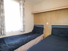 A bedroom with two single beds and a window with curtains at 610 Caravan in Bognor Regis