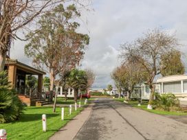 A paved road with trees and multiple caravans on each side at 610 Caravan in Bognor Regis