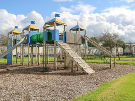 A playground structure with slides climbing nets and a tunnel in an outdoor area at 610 Caravan in Bognor Regis