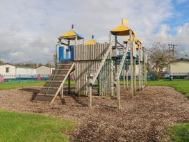 A wooden playground structure with climbing nets and slides on a mulch surface at 610 Caravan in Bognor Regis