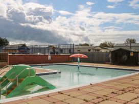 An outdoor swimming pool with a green slide shaped like a crocodile and a red mushroom-shaped water feature at 610 Caravan in Bognor Regis
