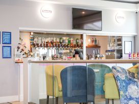 A bar area with liquor bottles and taps behind a glass railing with colorful upholstered chairs at 610 Caravan in Bognor Regis