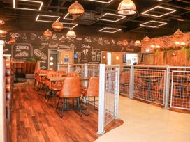 A restaurant dining area with brown chairs wooden tables pendant lights chalkboard menu on wall and metal railings at 610 Caravan in Bognor Regis