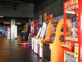 A row of arcade game machines along a wall in an indoor entertainment venue with colorful square patterns on the wall at 610 Caravan in Bognor Regis