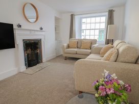 A living room with two beige sofas cushions fireplace TV and flowers on a table at 47 Church Street in Lyme Regis