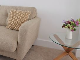 A beige sofa with a textured cushion next to a glass table with a vase of flowers at 47 Church Street in Lyme Regis