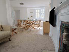 A living room with a sofa glass side table dining table with chairs and a fireplace at 47 Church Street in Lyme Regis