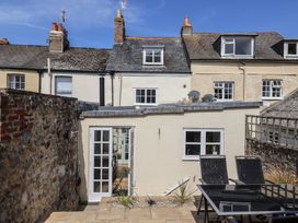 A paved patio area with black chairs and table outside a cream building with French doors at 47 Church Street in Lyme Regis