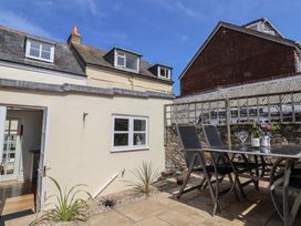 An outdoor patio with chairs and a table with wine and flowers at 47 Church Street in Lyme Regis