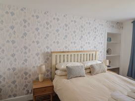 A bedroom with a double bed two bedside tables with lamps patterned wallpaper and built in shelves at 47 Church Street in Lyme Regis
