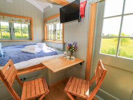A sleeping area with a bed and table at Goose Whistle Hut in Foxham