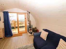 A room with a blue covered sofa with two patterned cushions a wood burning stove and glass doors opening to an outdoor area at Holbein in Matlock