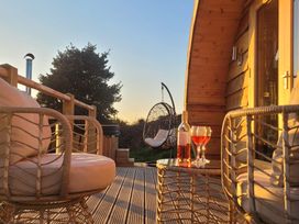 A wooden deck with two cushioned chairs a small table with a bottle and glasses of wine and a hanging chair at Holbein Matlock